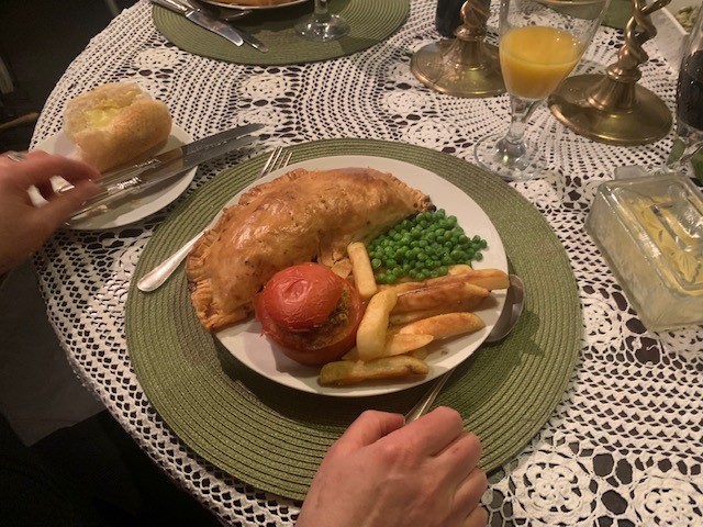 A pasty, stuffed tomato, chips and peas